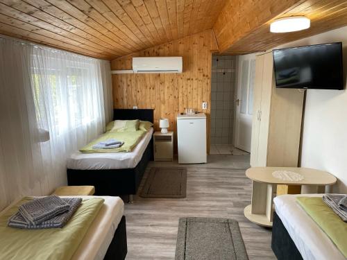 a small room with two beds and a television at Lenzl's Panzió in Szigetvár
