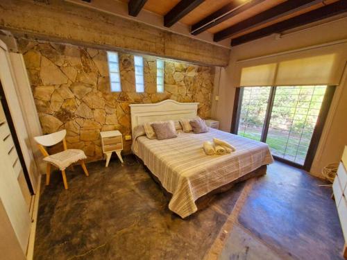 um quarto com uma cama grande e uma parede de pedra em Casa Chacras de Coria em Mayor Drumond