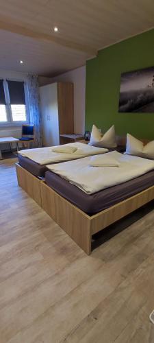twee bedden in een kamer met een groene muur bij Hotel Aits garni in Nordenham