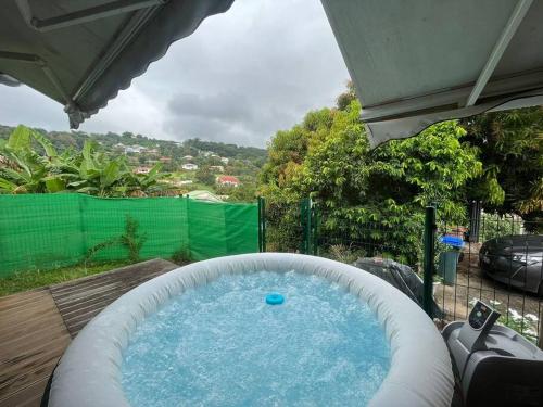 een groot zwembad met een parasol en een zwembad bij L'EdenKrys 2 avec son jacuzzi in La Trinité