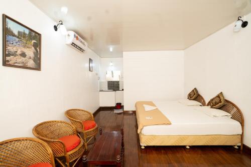 1 dormitorio con cama, sillas y mesa en Garggi Backwater Retreat en Kottayam