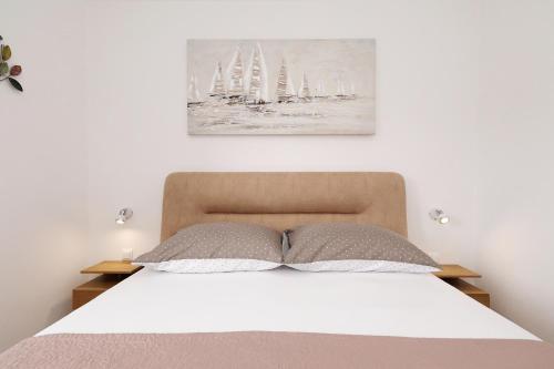 a bed with two pillows and a painting on the wall at Apartman Sipina 2 in Kukljica