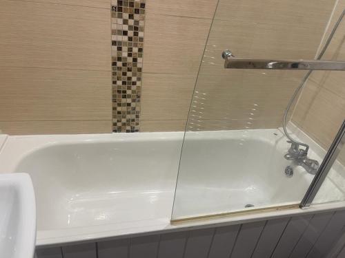 a bathroom with a tub with a glass shower at Warm Chiltern House in Luton