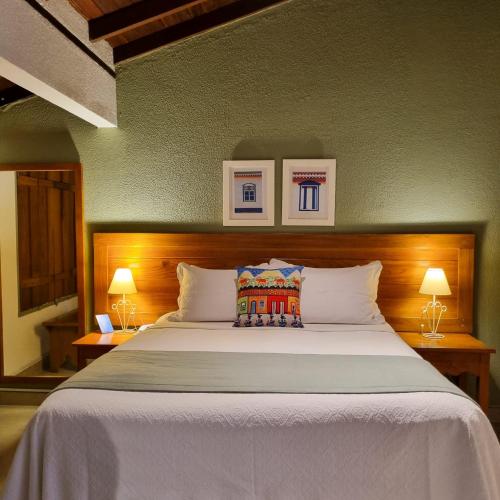 a bedroom with a large white bed with two lamps at Pouso 22 in Pirenópolis
