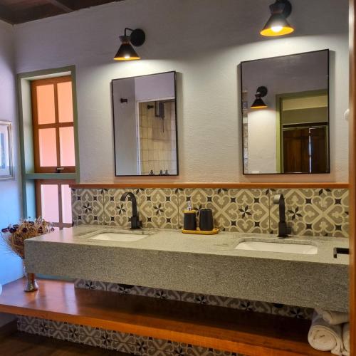 a bathroom with two sinks and two mirrors at Pouso 22 in Pirenópolis