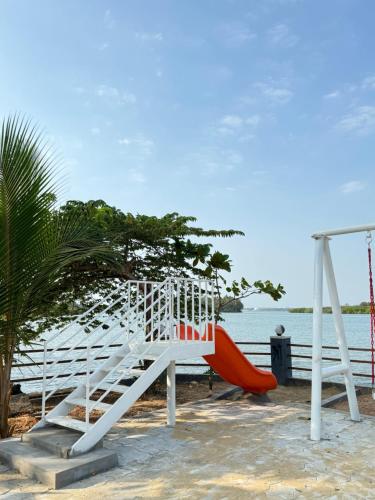 a playground with a red slide on the beach at The Glasswater By the Backwater Homestay in Kalyānpur