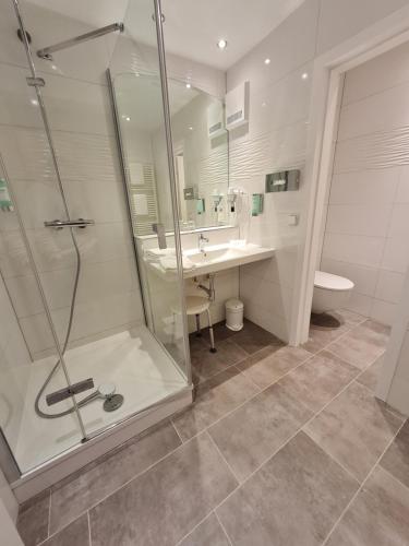 a bathroom with a shower and a sink and a toilet at Seehotel Fährhaus in Bad Zwischenahn