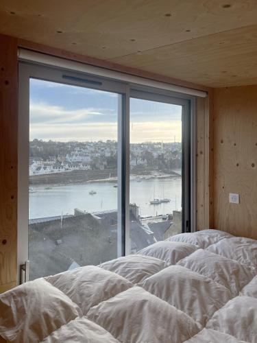- une chambre avec une grande fenêtre donnant sur l'eau dans l'établissement Beautiful wood house and view, à Audierne