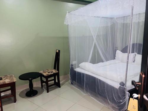 a bedroom with a canopy bed with a table and a stool at Suzie Kampala Uganda in Kampala
