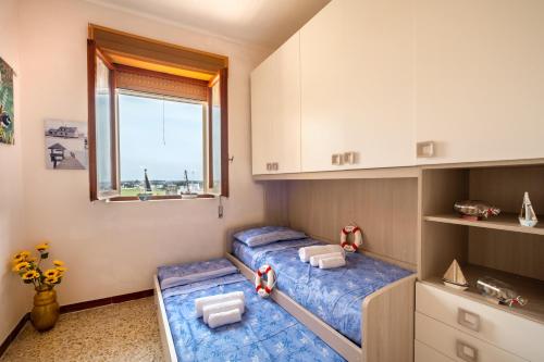 2 Betten in einem kleinen Zimmer mit Fenster in der Unterkunft The Sunrise Attico Panoramico in Porto Cesareo