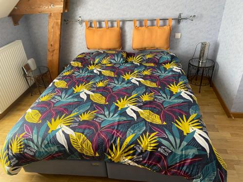 a bed with a colorful bedspread with flowers on it at Le Petitepinay in Moitron-sur-Sarthe