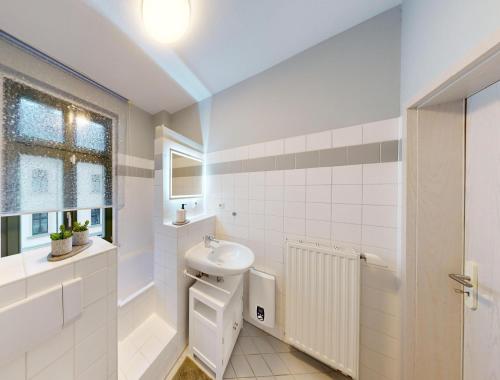 a white bathroom with a sink and a toilet at CozyHome Markkleeberg Mitte in Markkleeberg
