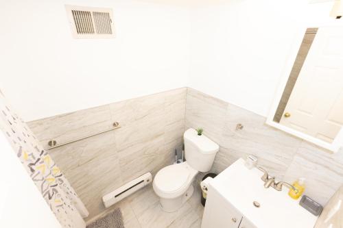 a white bathroom with a toilet and a sink at Mins to NYC! Urban Oasis 2-BR home with King & Queen Beds in Jersey City