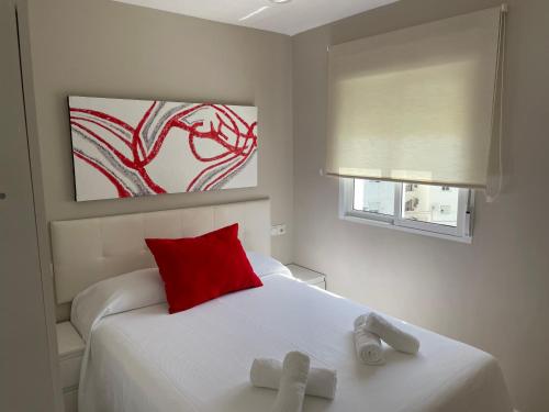 1 dormitorio con cama blanca y almohada roja en Ritual Sevilla, Fedriani, en Sevilla