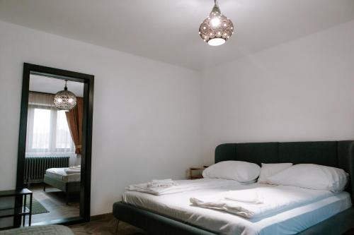 Schlafzimmer mit einem Bett mit weißer Bettwäsche und einem Spiegel in der Unterkunft Csongor Lak in Igricetanya