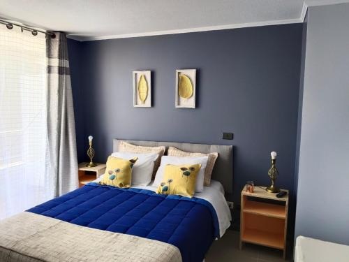 um quarto com paredes azuis e uma cama com almofadas amarelas em Vivir en Santiago em Santiago