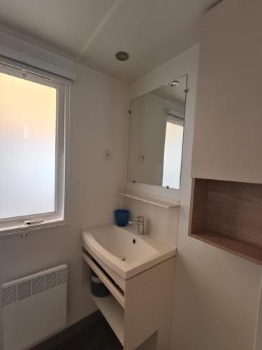 une salle de bain blanche avec un lavabo et un miroir dans l'établissement Entre Mer et Etang !, à Canet