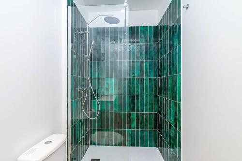 y baño con ducha de azulejos verdes y aseo. en Havre de Paix près de la Capitale, en Bagnolet