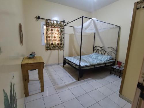 1 dormitorio con cama con dosel y mesa en Chez Sandrine, en Ouoran