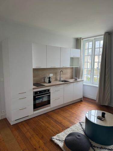 - une cuisine avec des placards blancs, un évier et une table dans l'établissement Le Hêtre Pourpre, à Bayeux