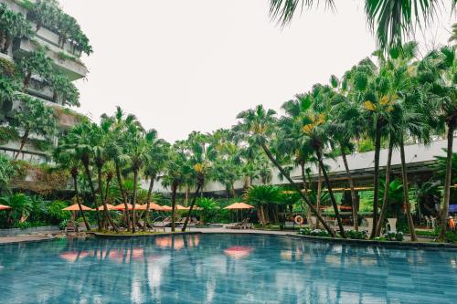 a pool at a resort with palm trees and umbrellas at Rosee Villa - Green Villa with private Pool in Vĩnh Phúc