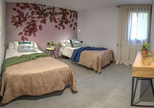 a bedroom with two beds and a tree on the wall at Las Horneras de Cobeta. Apartamento Andrea in Cobeta
