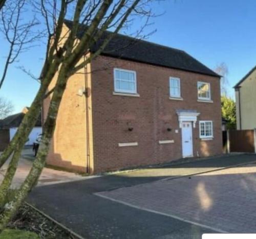 a brick building with a white door on a street at Cathedral Walk 3 Bed Coachhouse in Lichfield
