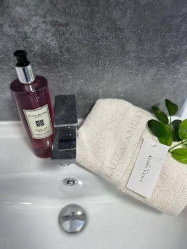a sink with a bottle of soap and a towel at Lichfield City Cathedral Walk 3 Bedroom Coachhouse in Lichfield