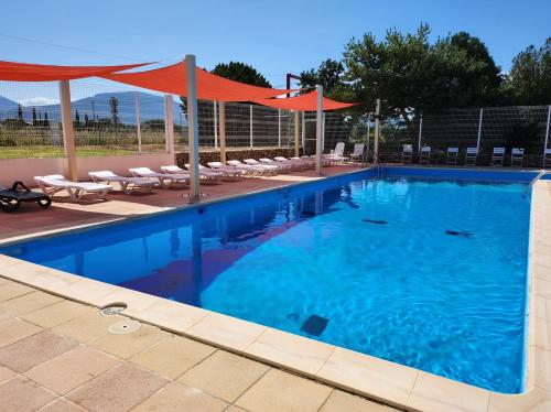 une grande piscine avec des chaises et un auvent orange dans l'établissement Mobil home confortable Gorges du Verdon, à Sainte-Croix-de-Verdon