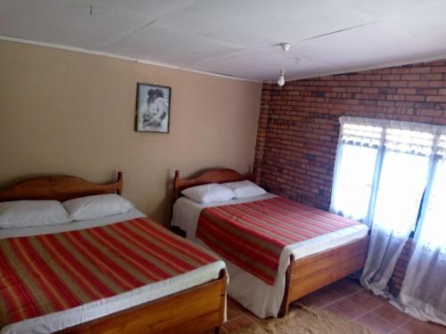 a bedroom with two beds and a brick wall at Maliga Inn in Gampola