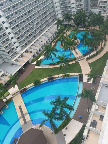 uitzicht op een groot zwembad met palmbomen bij Shell Residences condotel Staycation in Manilla