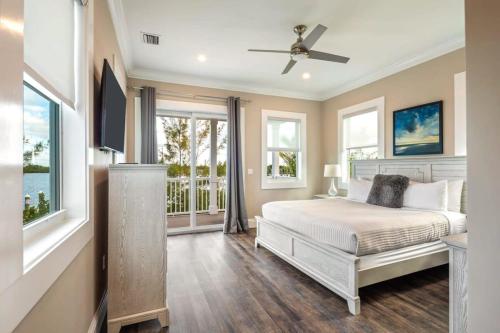 a bedroom with a bed with a ceiling fan and windows at Smooth Sailing by Brightwild-Pool & Boat Dock in Key West