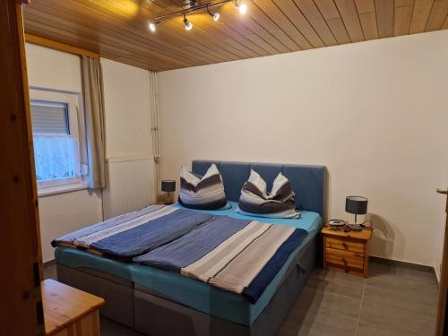 a bedroom with a blue bed with pillows on it at Pension Arbersonne in Bayerisch Eisenstein