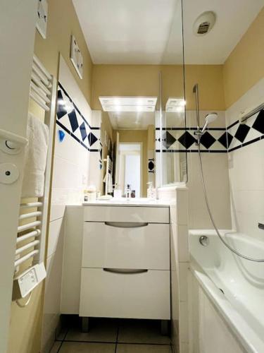 une salle de bain blanche avec un lavabo et un miroir dans l'établissement Embruns - Appartement au calme, à Talmont-Saint-Hilaire
