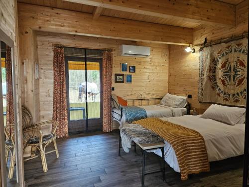 Duas camas num quarto com paredes de madeira em Bosquey Ranch B&B em Alice Castello