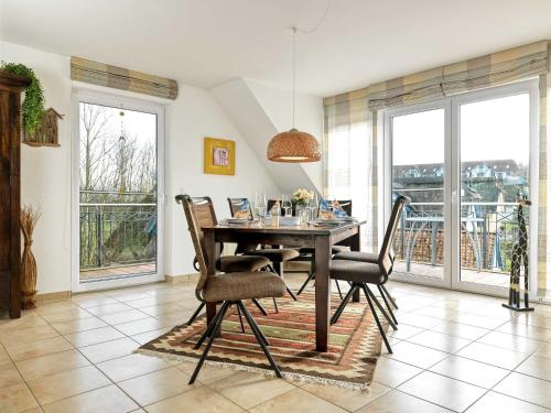 ein Esszimmer mit einem Tisch, Stühlen und Fenstern in der Unterkunft Landhaus Residenz Ostsee Meeresbrise in Insel Poel