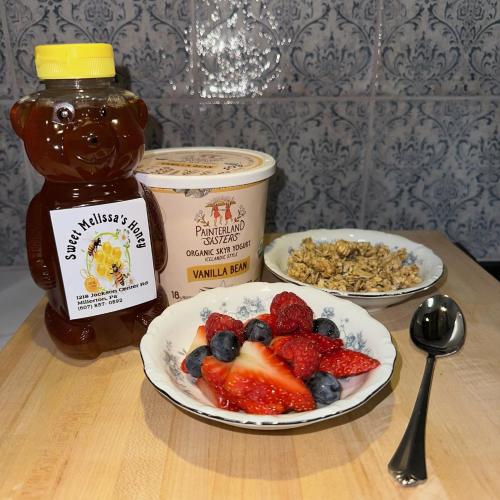 a table with a plate of fruit and a jar of honey at 37 Oak Ridge House in Wellsboro