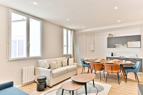 a living room with a couch and a table with chairs at Appartement spacieux à 5 minutes de la capitale in Bagnolet