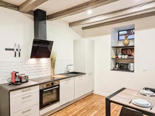 uma cozinha com armários brancos e uma mesa em Le T3 du Carnot em Annecy