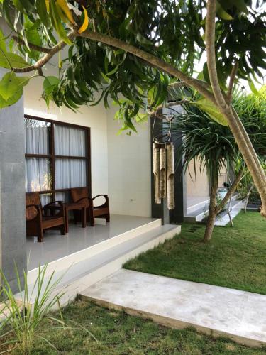 a house with a porch with a table and chairs at Maha di Nusa Lembongan in Nusa Lembongan