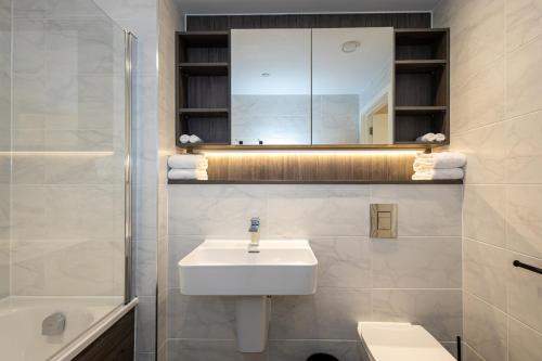 W białej łazience znajduje się umywalka i lustro. w obiekcie Nuvola Suite by CasaCity w Manchesterze