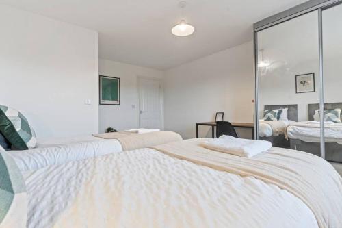 a white bedroom with two beds and a mirror at Anglian Retreat - Close to City Centre - Free Parking, Fast Wifi and Smart TV by Yoko Property in Coventry