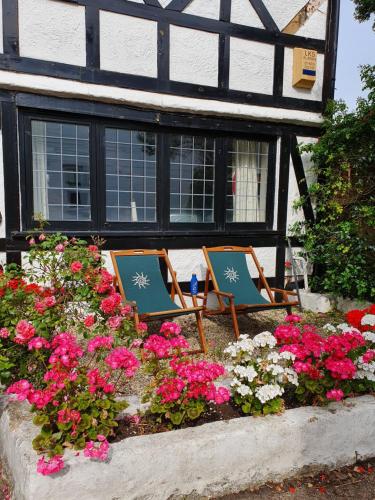 two chairs in front of a house with flowers at Bournemouth secluded cottage 10mins walk to beach in Bournemouth