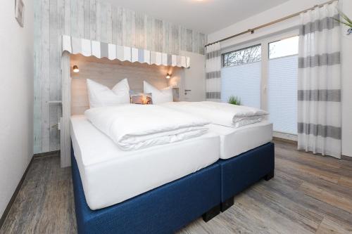 a large bedroom with a large bed with white sheets at Haus Strandkorb mit Frühstücksoption in Bensersiel