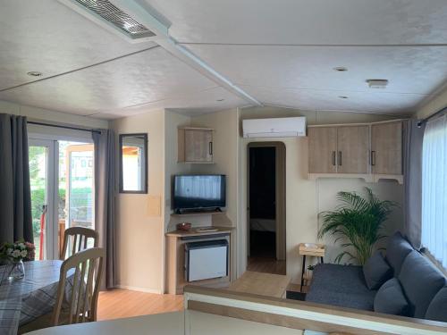 Mobil home LAC DES REVES في لات: غرفة معيشة بها أريكة زرقاء وتلفزيون