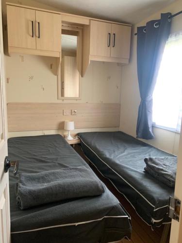 deux lits dans une chambre avec une fenêtre dans l'établissement Mobil home LAC DES REVES, à Lattes