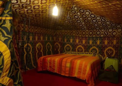 a bedroom with a bed in a room with a patterned wall at Sahara Berber Camp in Zagora