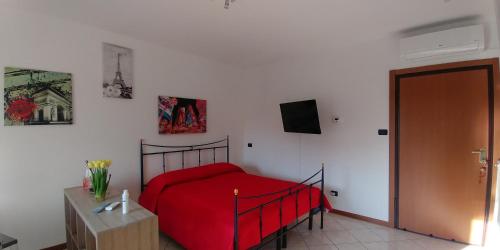 sypialnia z czerwonym łóżkiem i telewizorem na ścianie w obiekcie La Fenice w mieście Arcore