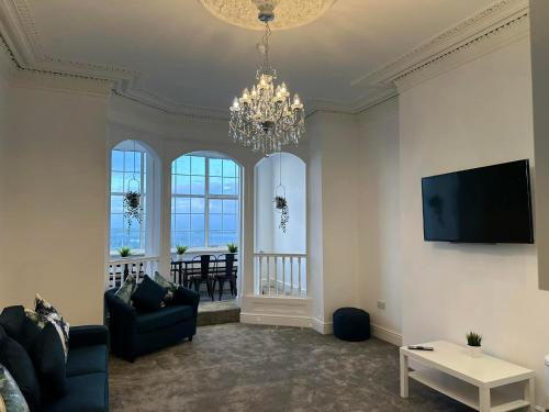 a living room with a chandelier and a table at New Sandpiper Apartments in Fleetwood