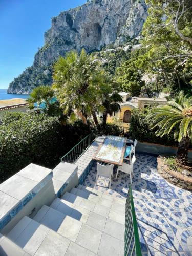 a patio with a table and chairs and a mountain at La Cuchina in Capri